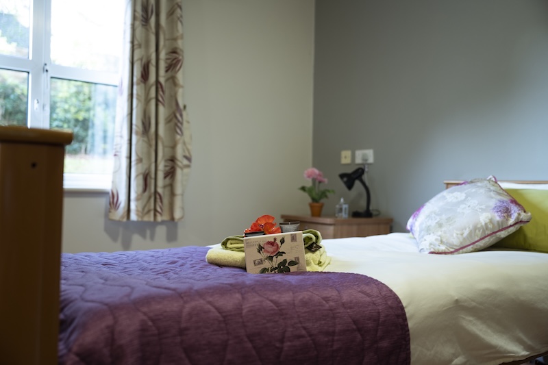 towels made up on a fresh bed with white and purple bedding